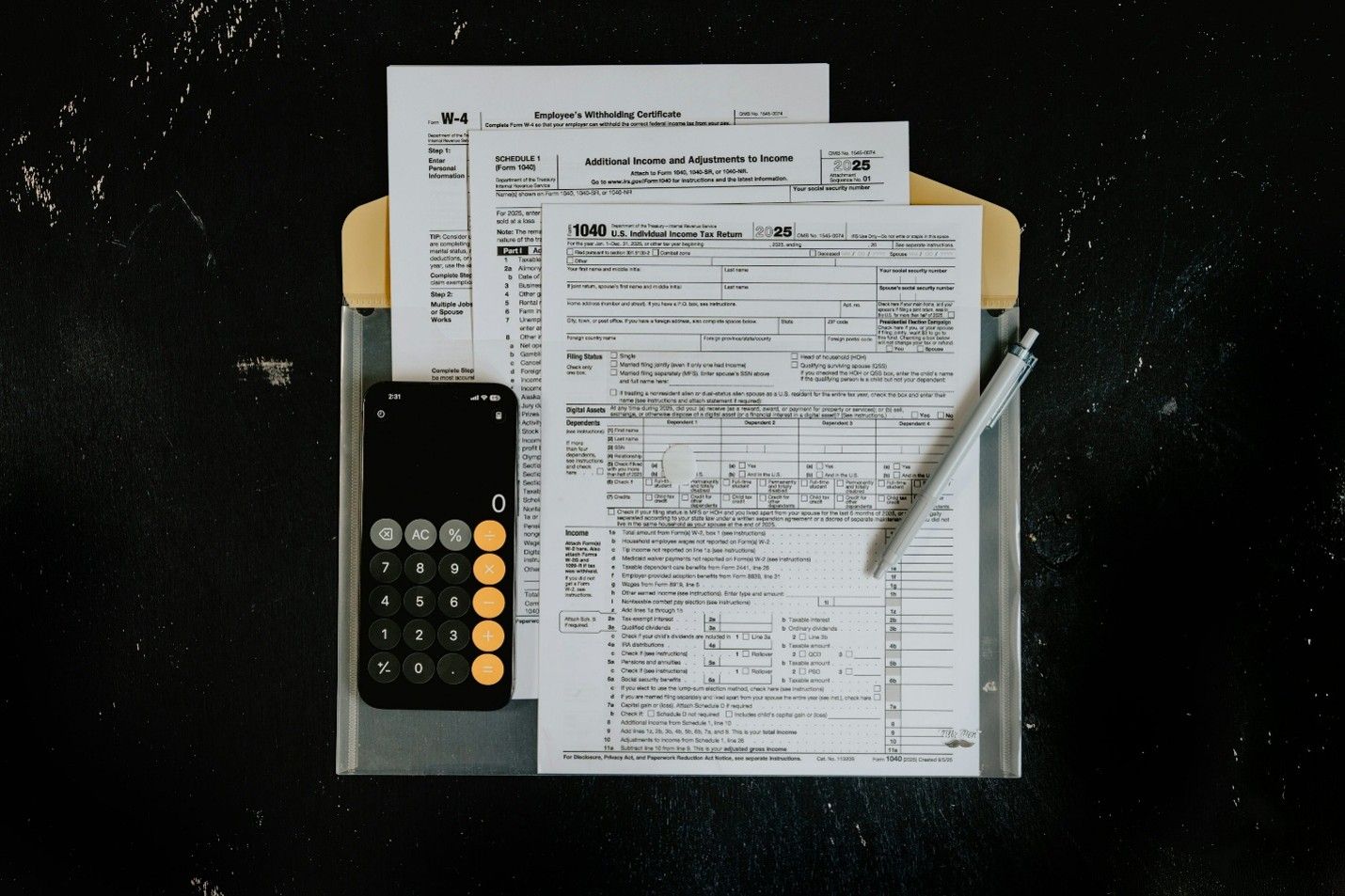 IRS Form 1040 and Schedule 1 tax forms with a calculator and pen