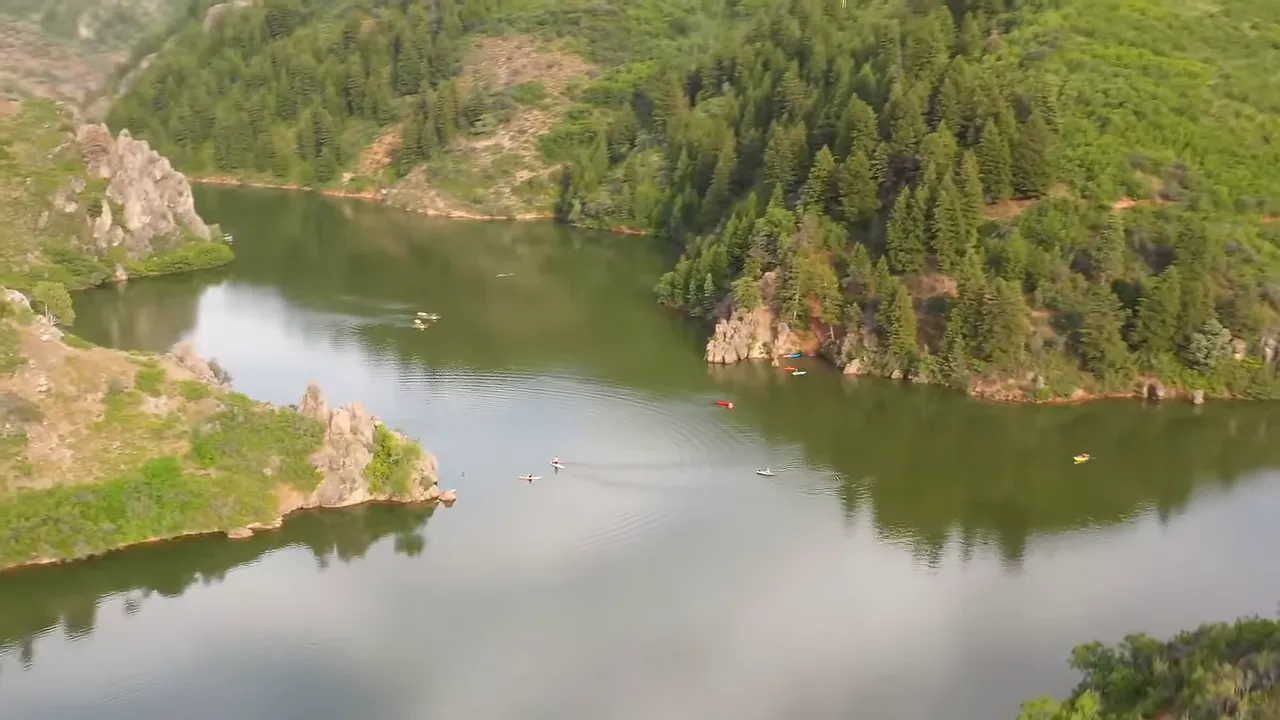A turquoise reservoir surrounded by cliffs and pine trees ideal for paddle boarding