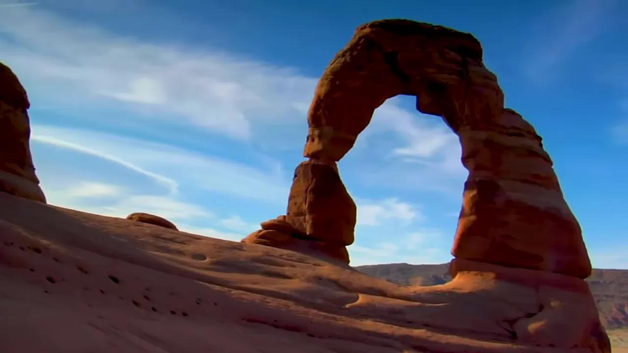 Hiking trail approaching a freestanding natural arch carved from red sandstone