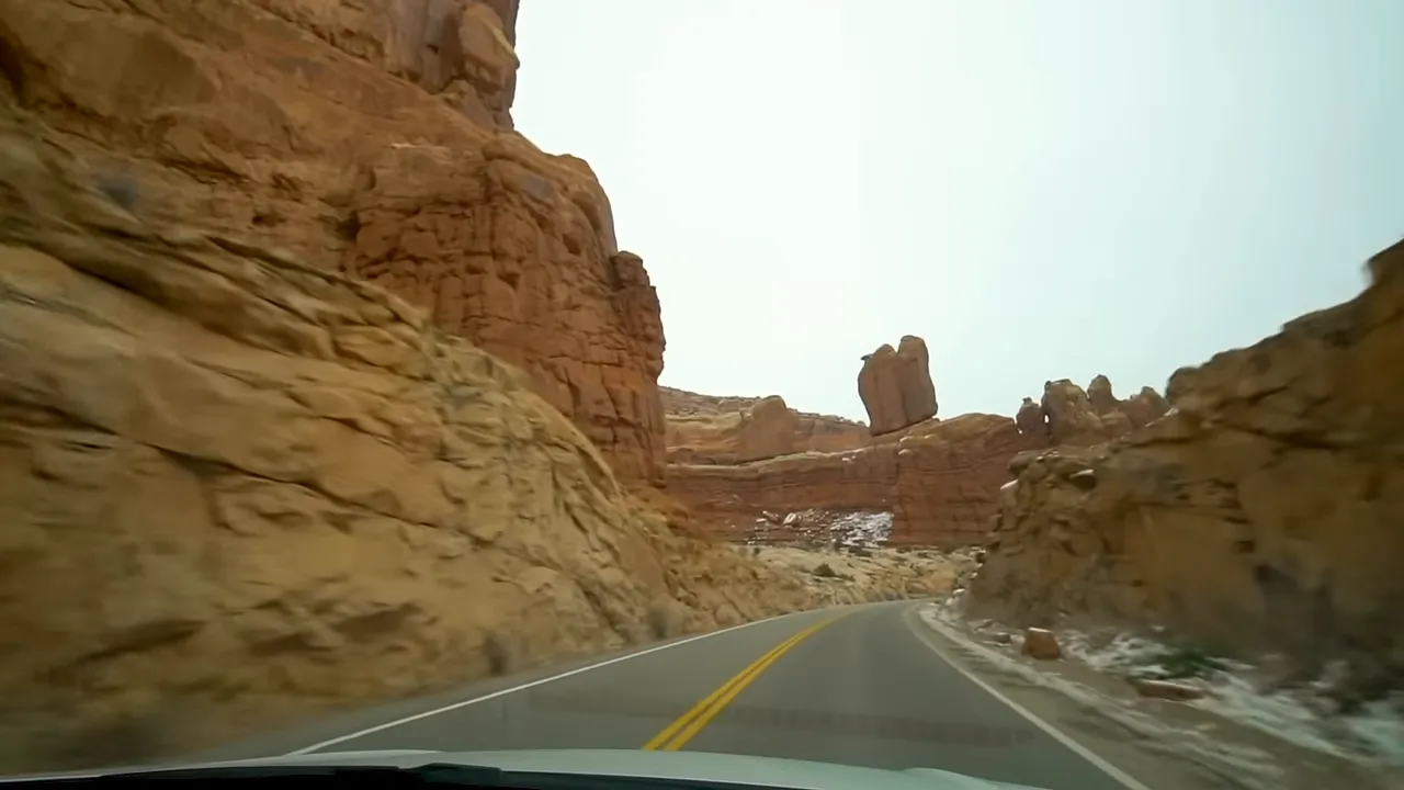 Wide view of red rock formations and a paved trail