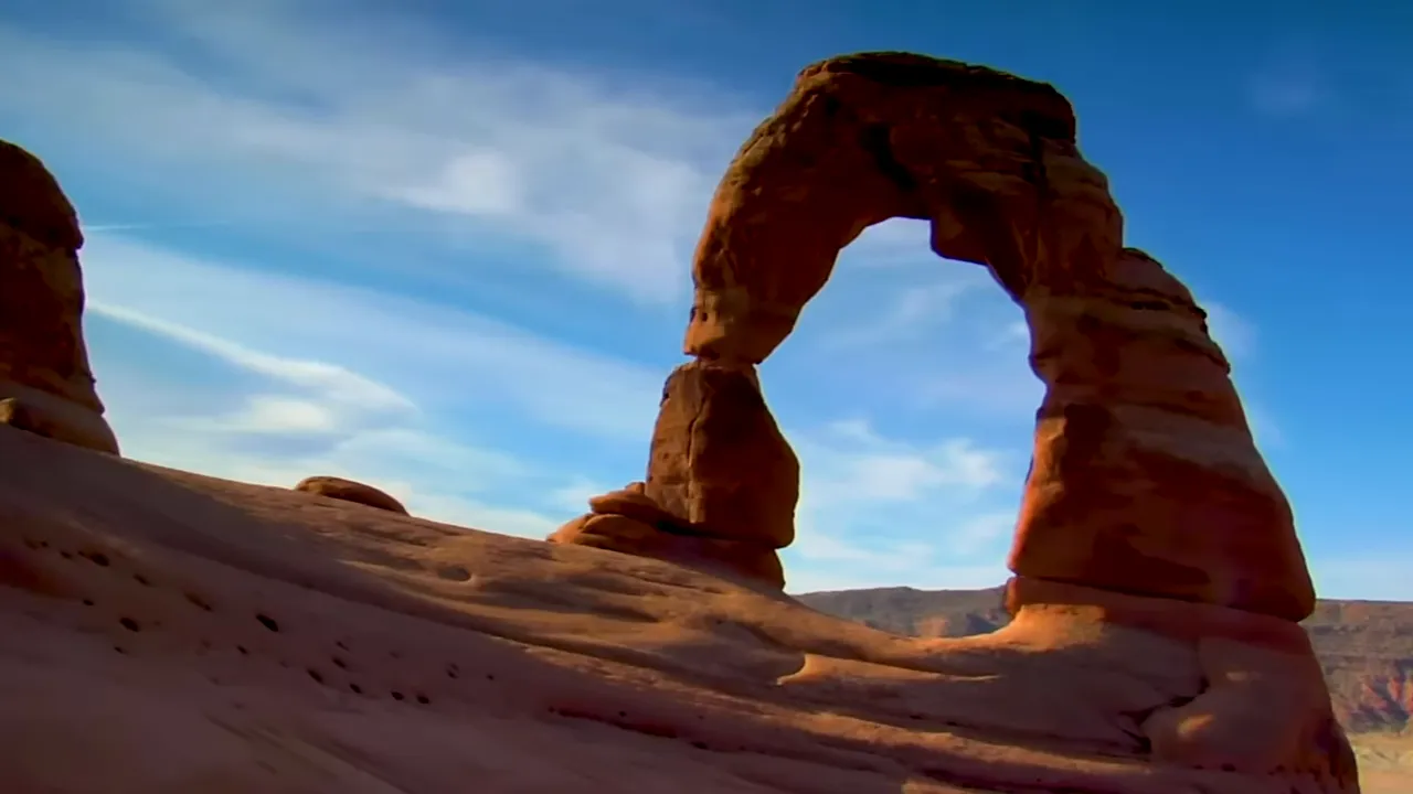 Natural stone arch framed by clear sky and desert surroundings