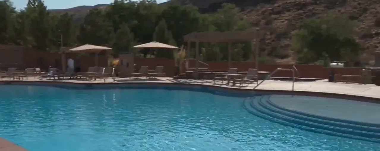 Family-friendly pool with steps, umbrellas and lounge chairs at Zion Canyon Hot Springs