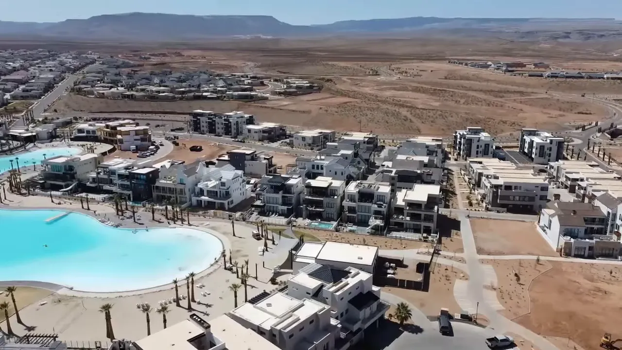 Aerial view of a large man‑made lagoon with adjacent modern homes and new development in St George.