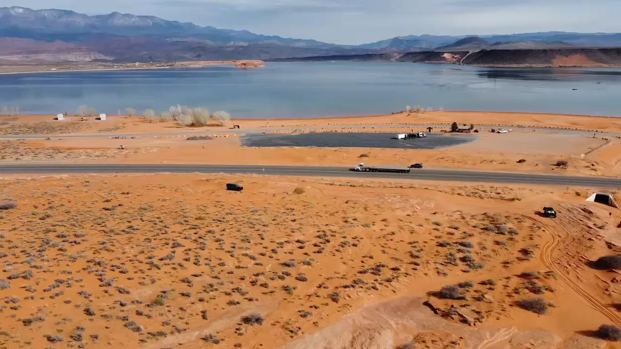 High-resolution aerial view of a lake and shoreline with desert foreground and distant mountains near St. George.