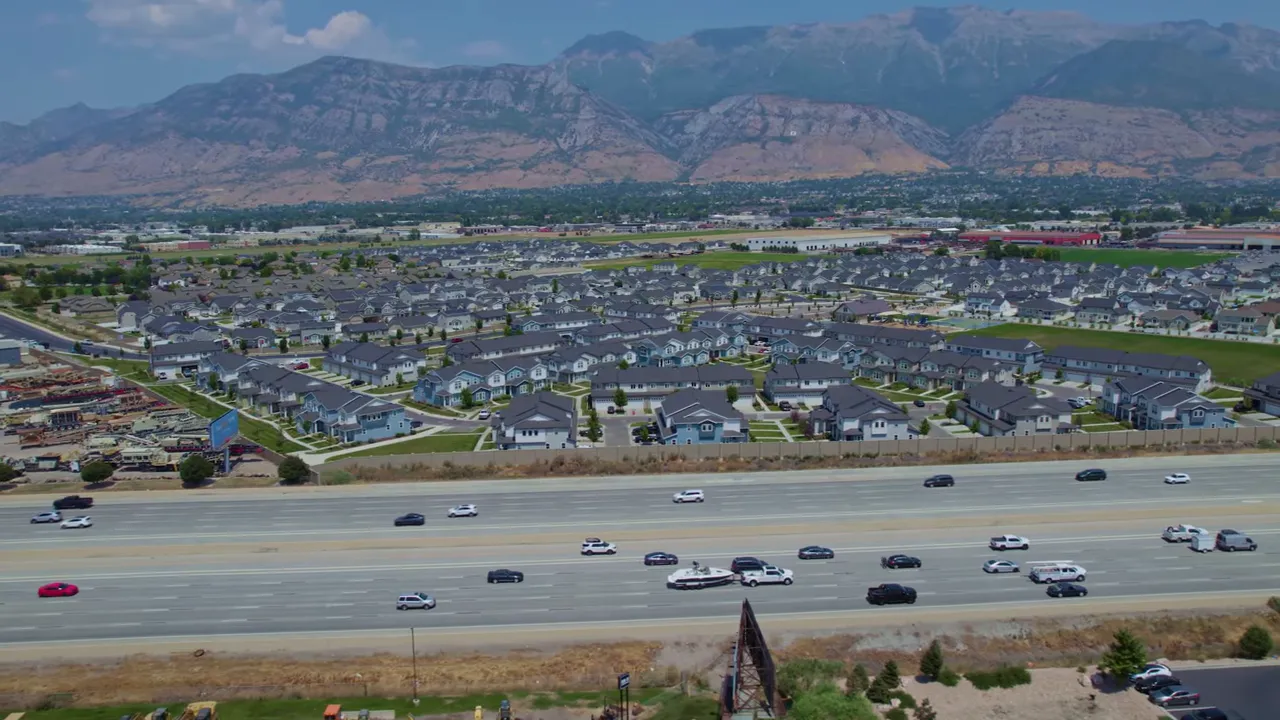 Panoramic aerial of a large residential subdivision, freeway in foreground and mountains in background
