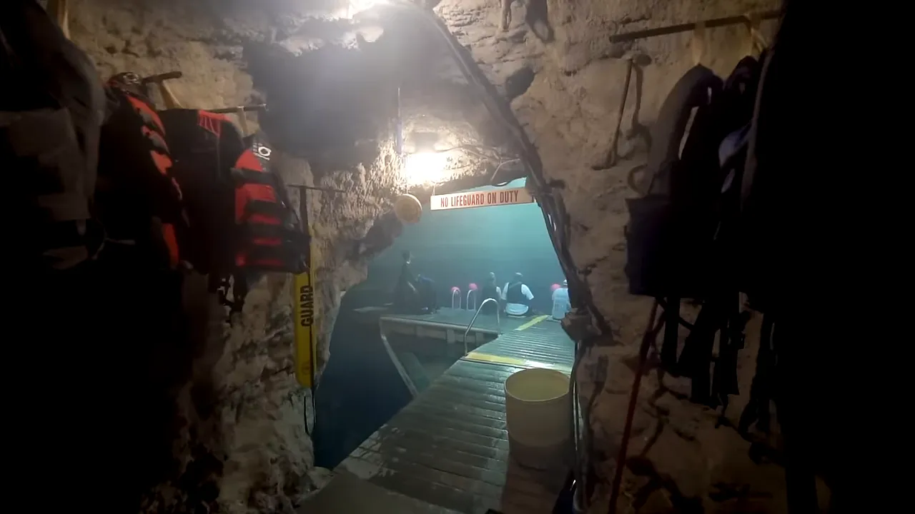Interior view of a geothermal mineral dome and warm turquoise water, showing visitors entering a cave-like doorway to reach the thermal pool