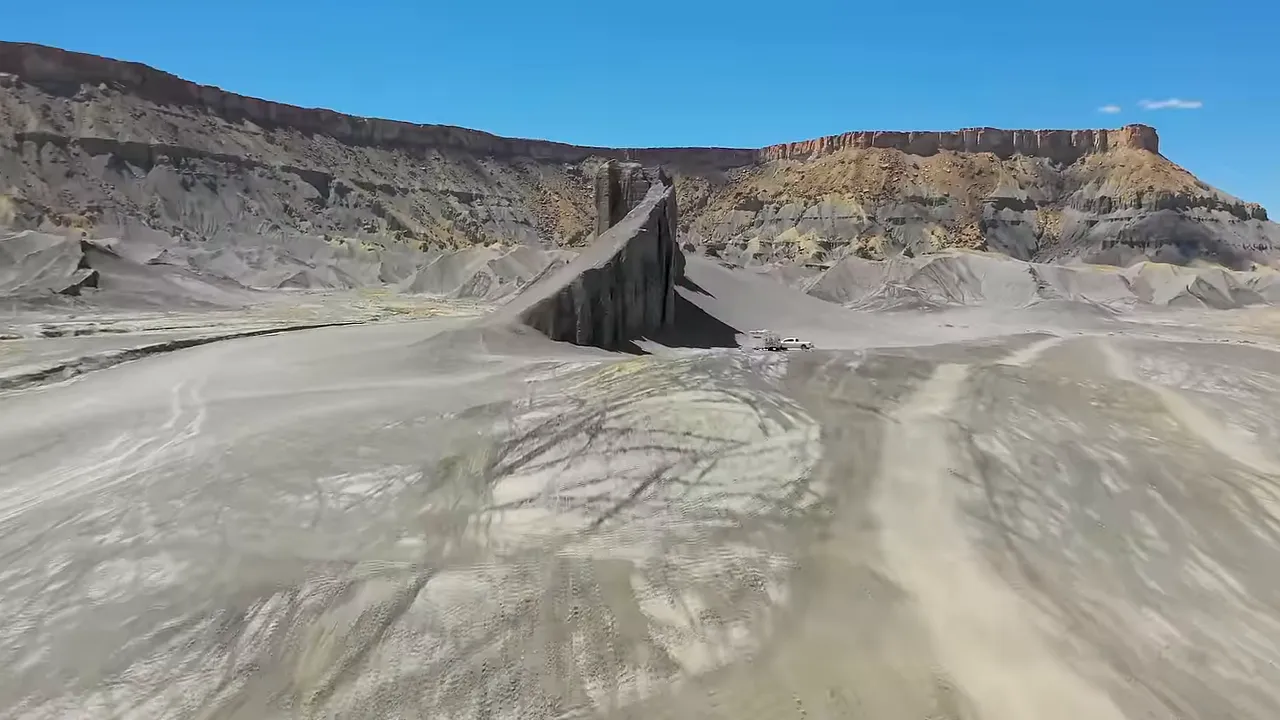 Desert ridges and natural dirt-bike jumps with riders on the horizon, showing a landscape suited to off-road recreation