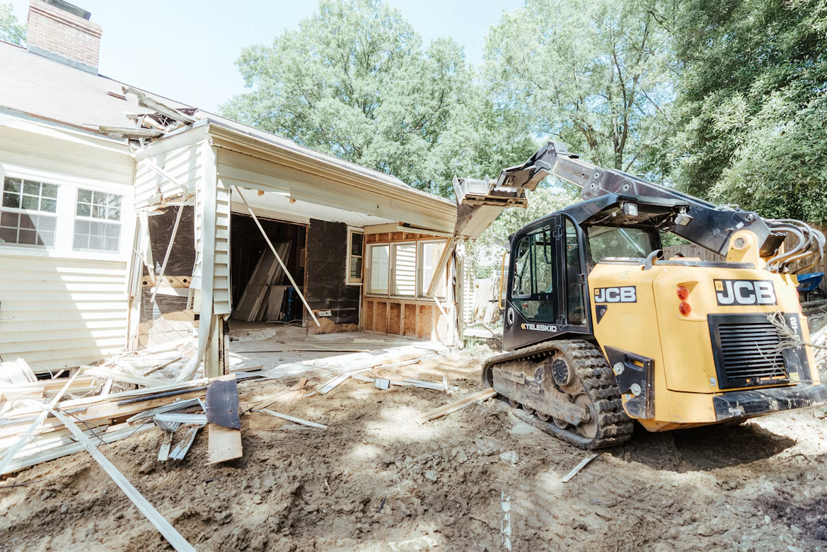 Bulldozer parked in front of a storm-damaged house